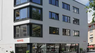 Das Bild zeigt ein modernes, mehrstöckiges Gebäude mit großen Fenstern. An der Fassade ist das Logo "SWG" und die Beschriftung "KUNDENZENTRUM" zu sehen. 